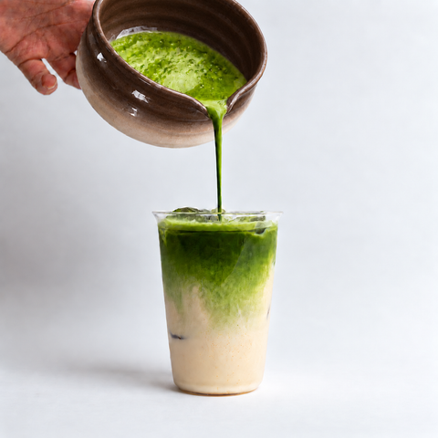 a person pouring green liquid into a glass
