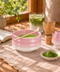 a bowl of green tea with a spoon next to a glass of green tea