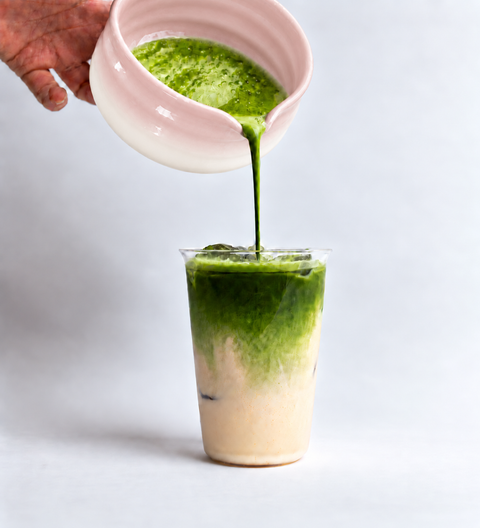 a person pouring green liquid into a glass