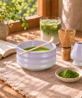 a bowl of green tea with a spoon next to a glass of green tea