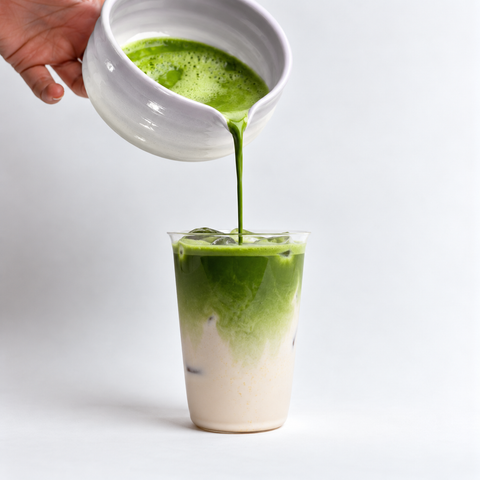 a person pouring green liquid into a glass